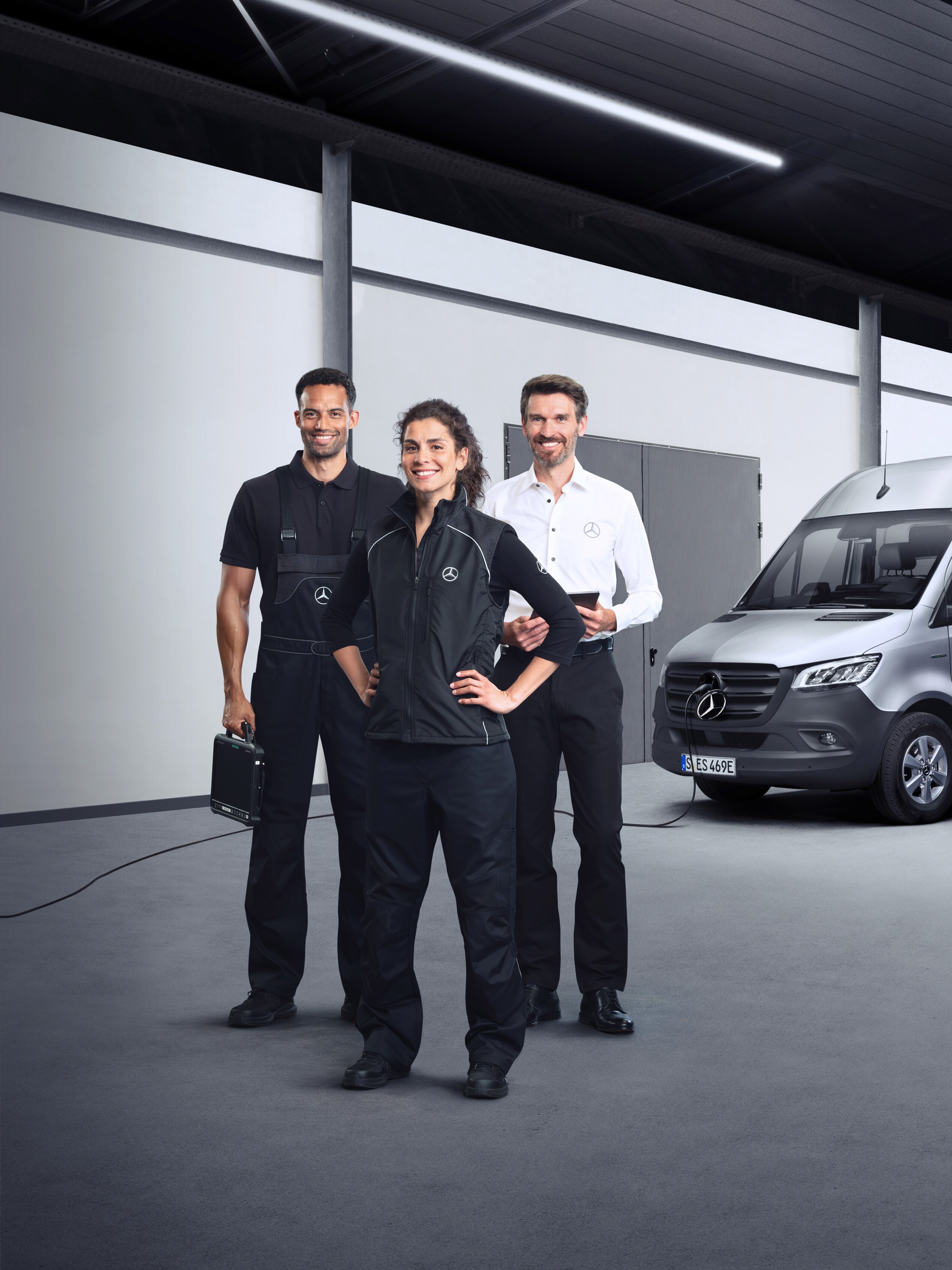 Drie medewerkers staan voor een zilveren Mercedes-Benz eSprinter met aangesloten laadkabel als symbool voor service elektrische bedrijfswagens.