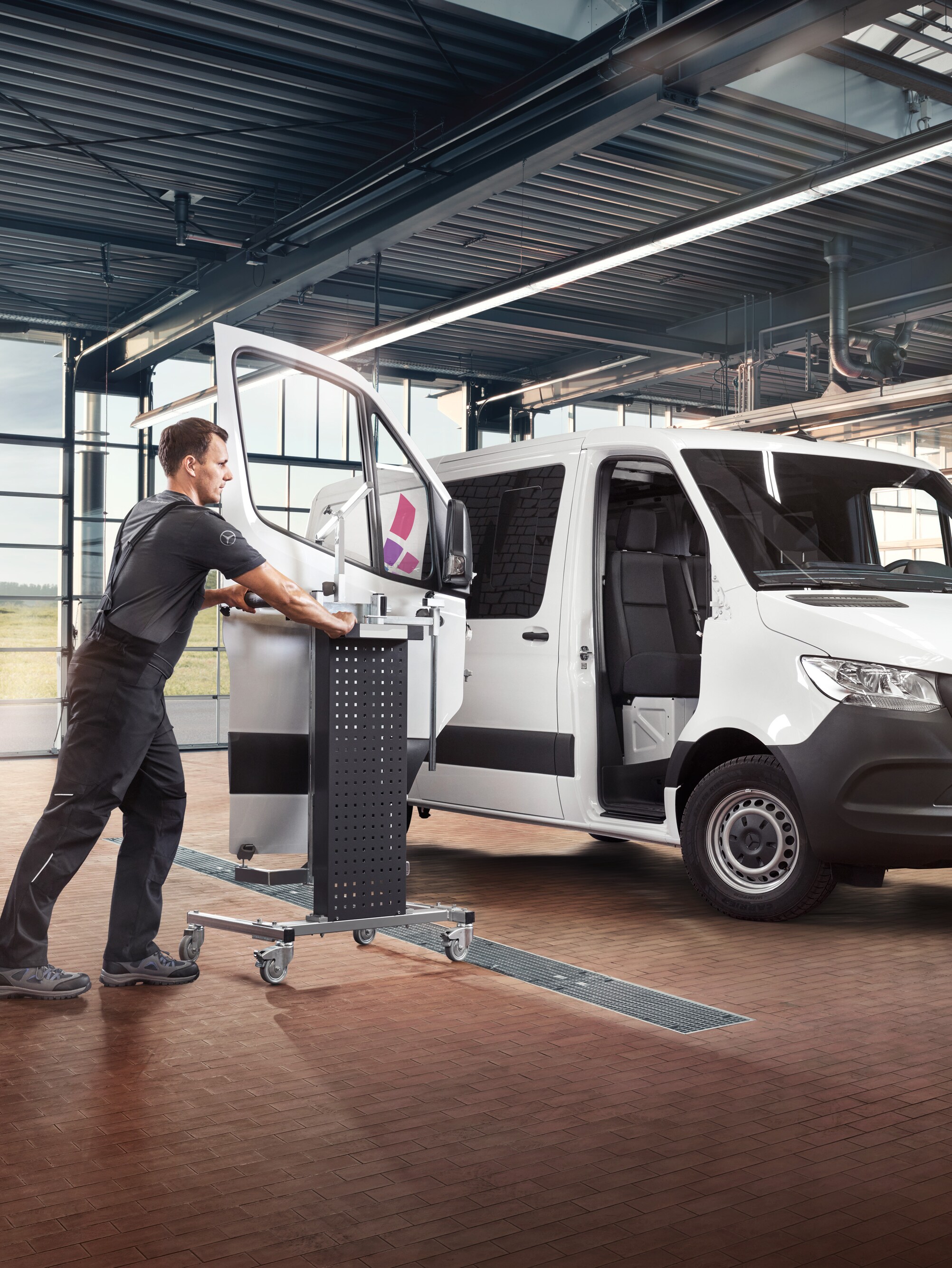Monteur repareert de passagiersdeur van een witte Mercedes-Benz Sprinter Gesloten Bestelwagen in de werkplaats.