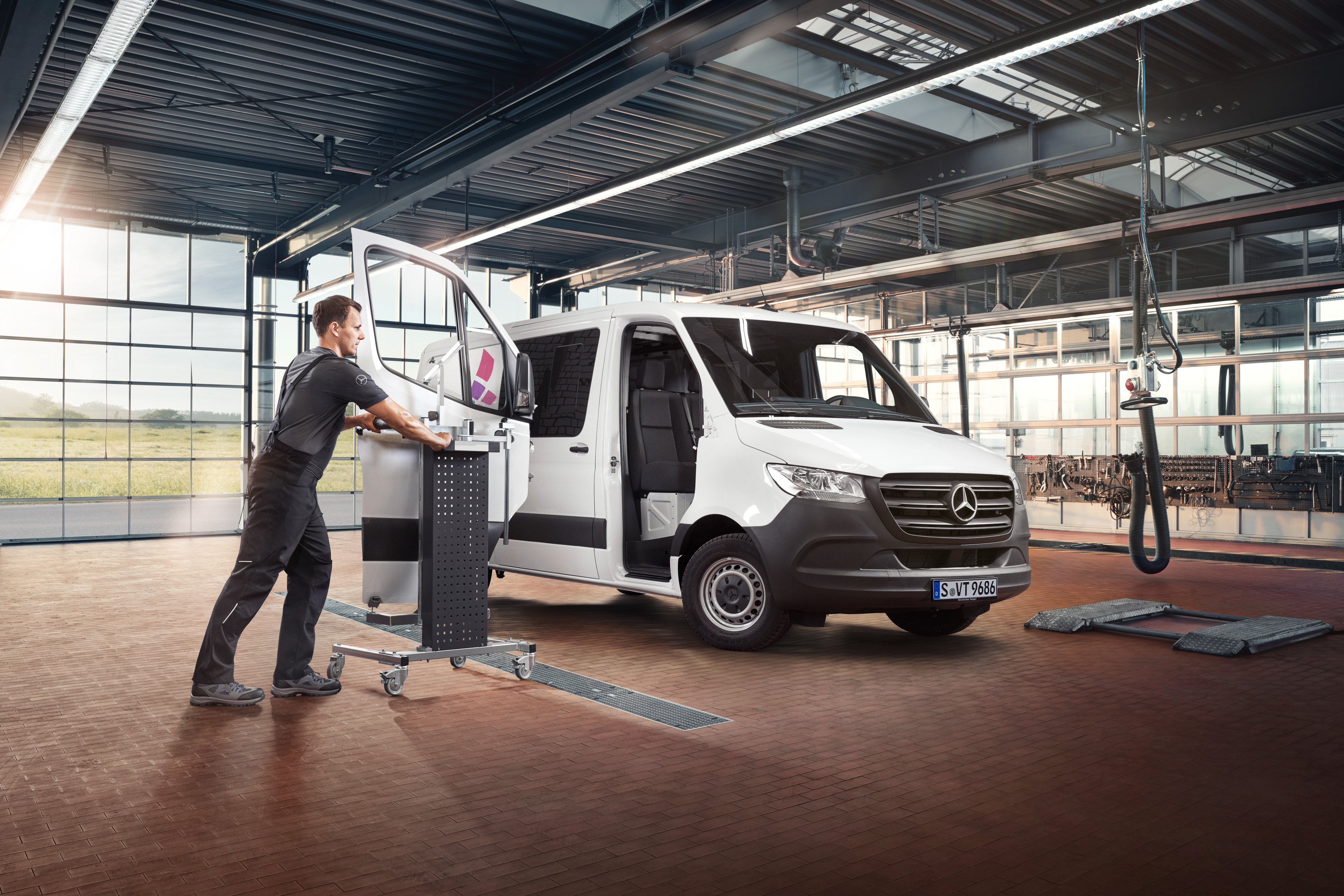 Mercedes-Benz | Servicesoverzicht | Reparatie Een monteur onderhoudt de bijrijdersdeur van een witte Mercedes-Benz Sprinter.