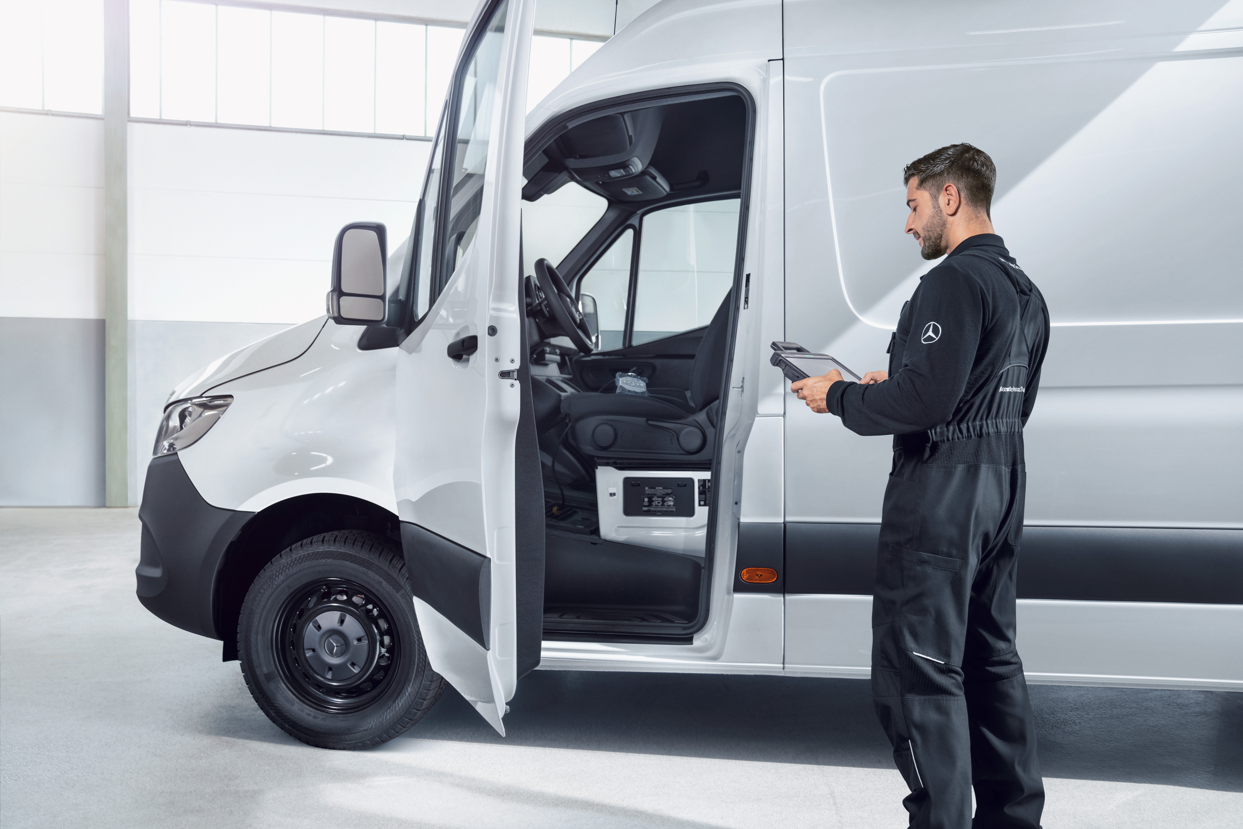 Mercedes-Benz | Bedrijfswagen Fleet Services | Voertuigonderhoud Een monteur controleert een witte Mercedes-Benz Sprinter Gesloten Bestelwagen met een tablet.