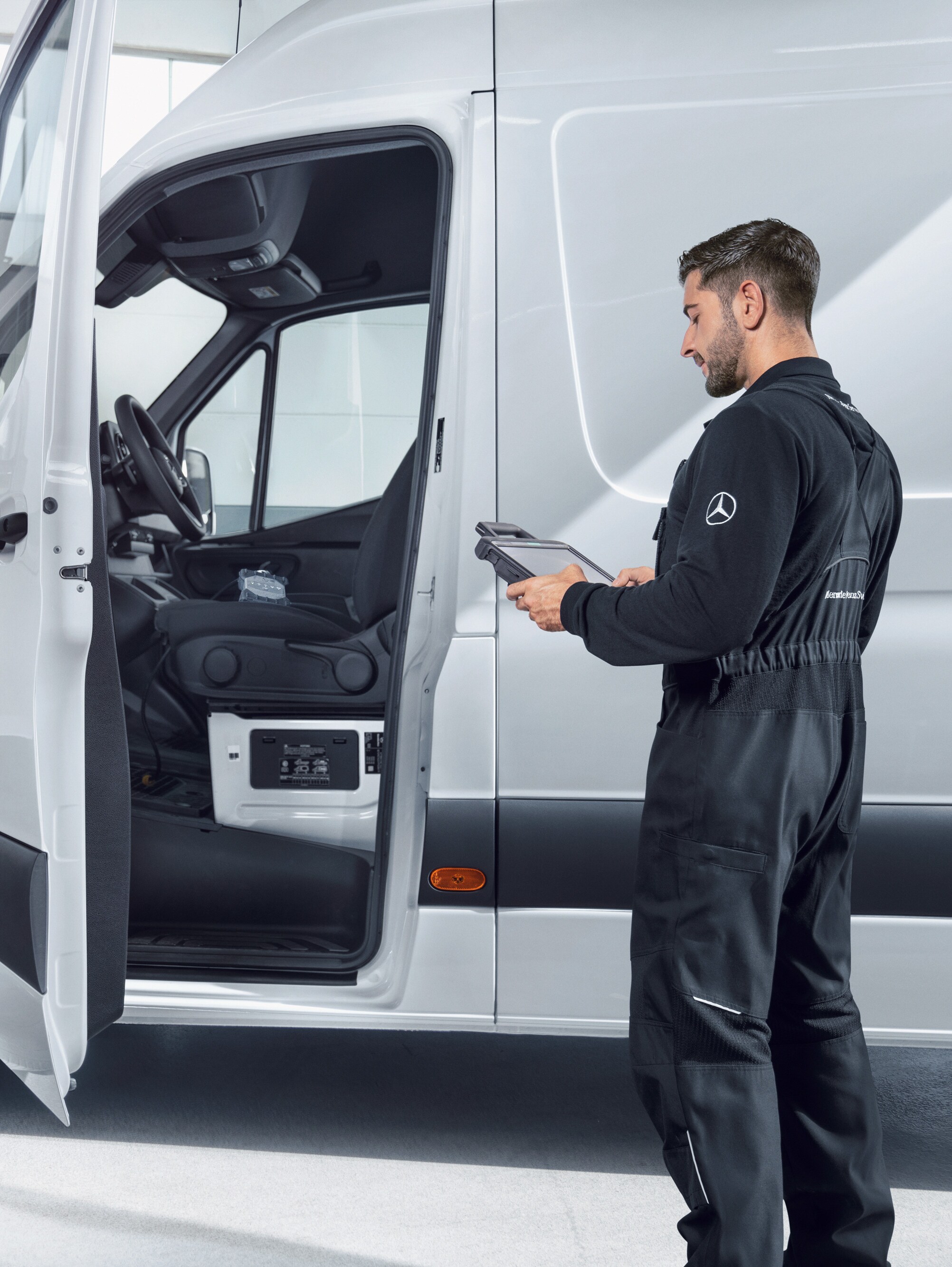 Een medewerker die een Mercedes-Benz bestelwagen inspecteert en betrouwbare servicekwaliteit biedt voor onderhoud en reparaties.