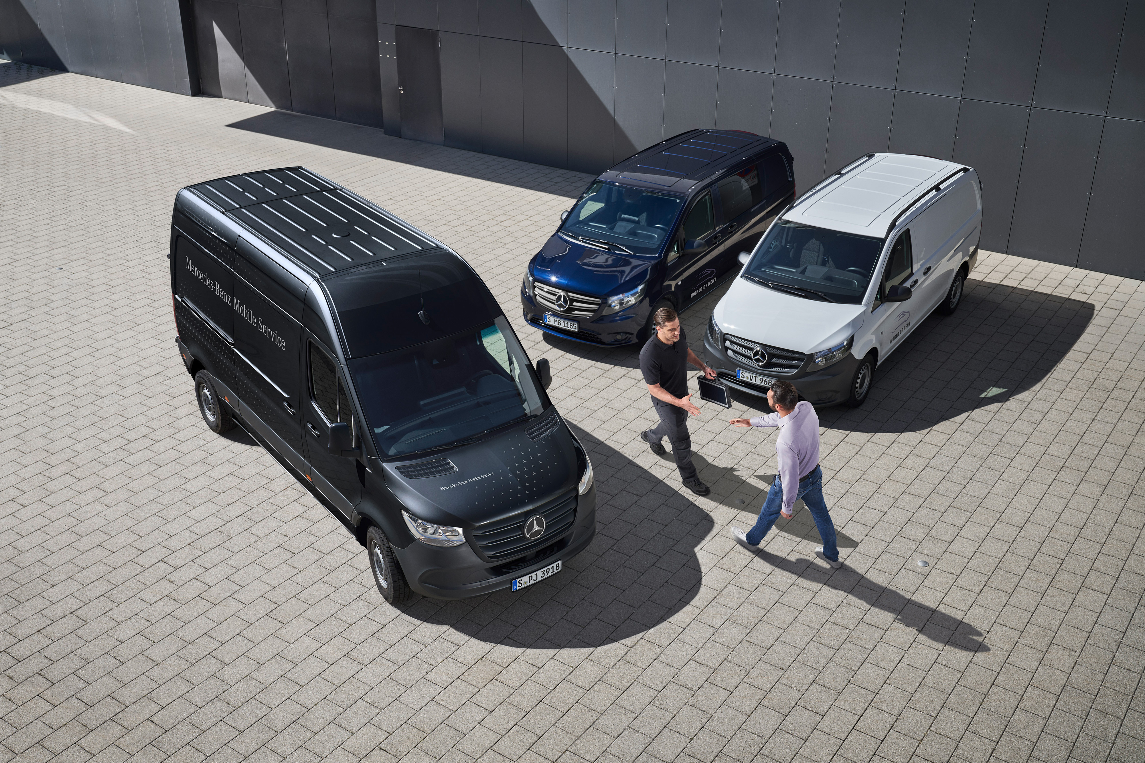 Mercedes-Benz | Servicesoverzicht | Mobiele Service Twee mannen begroeten elkaar tussen Mercedes-Benz bestelwagens.