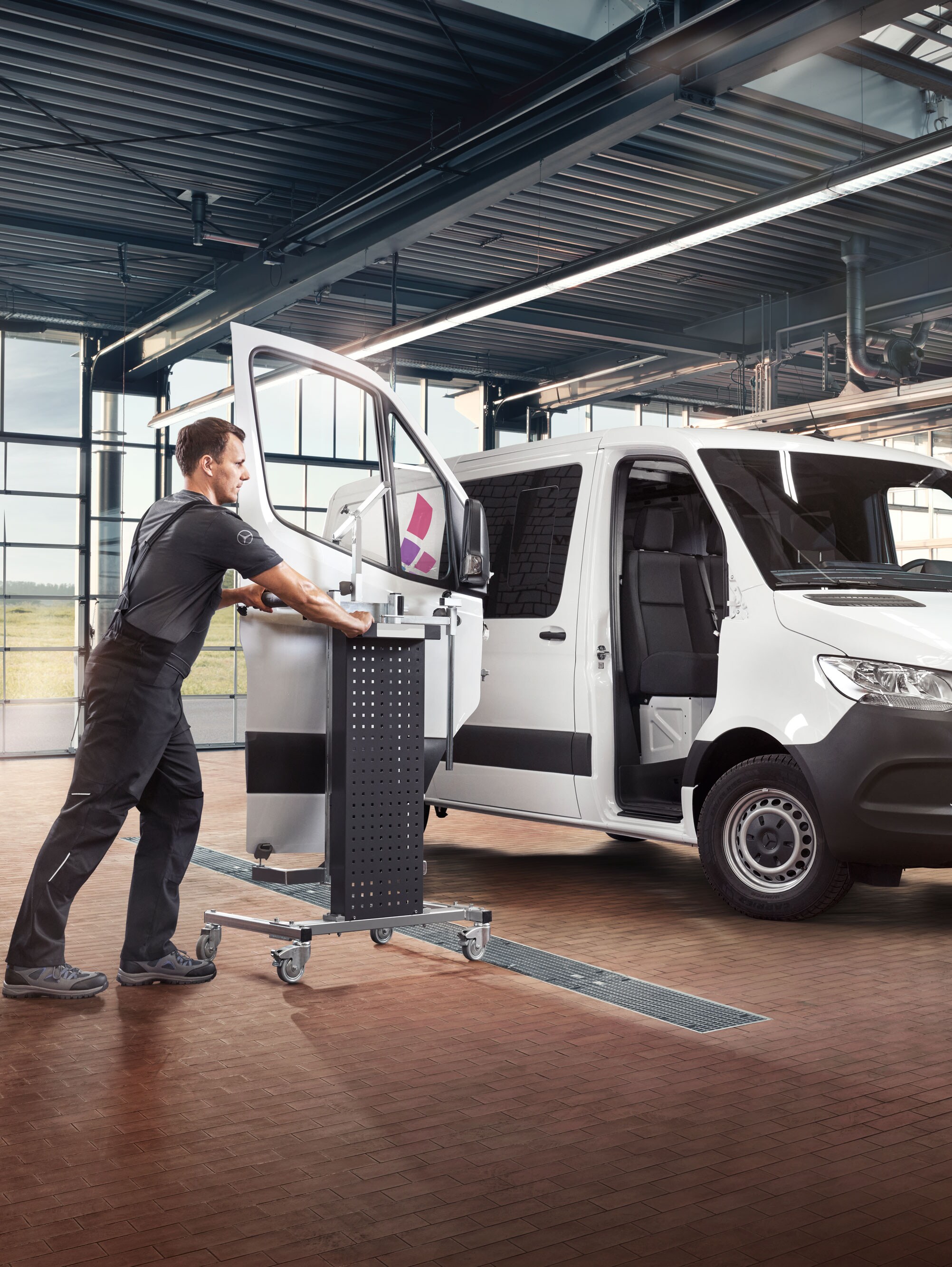 Monteur monteert de deur van een witte Mercedes-benz Sprinter Gesloten Bestelwagen.