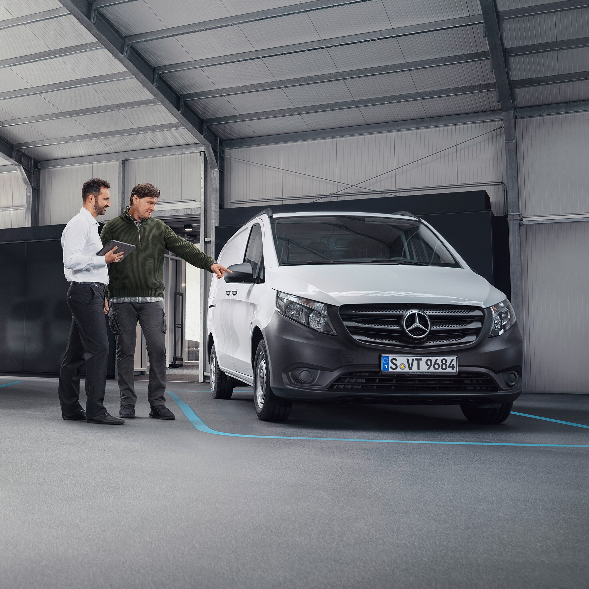 Mercedes-Benz klantenservicemedewerker met klant op een servicepartnerlocatie voor een bedrijfswagen.