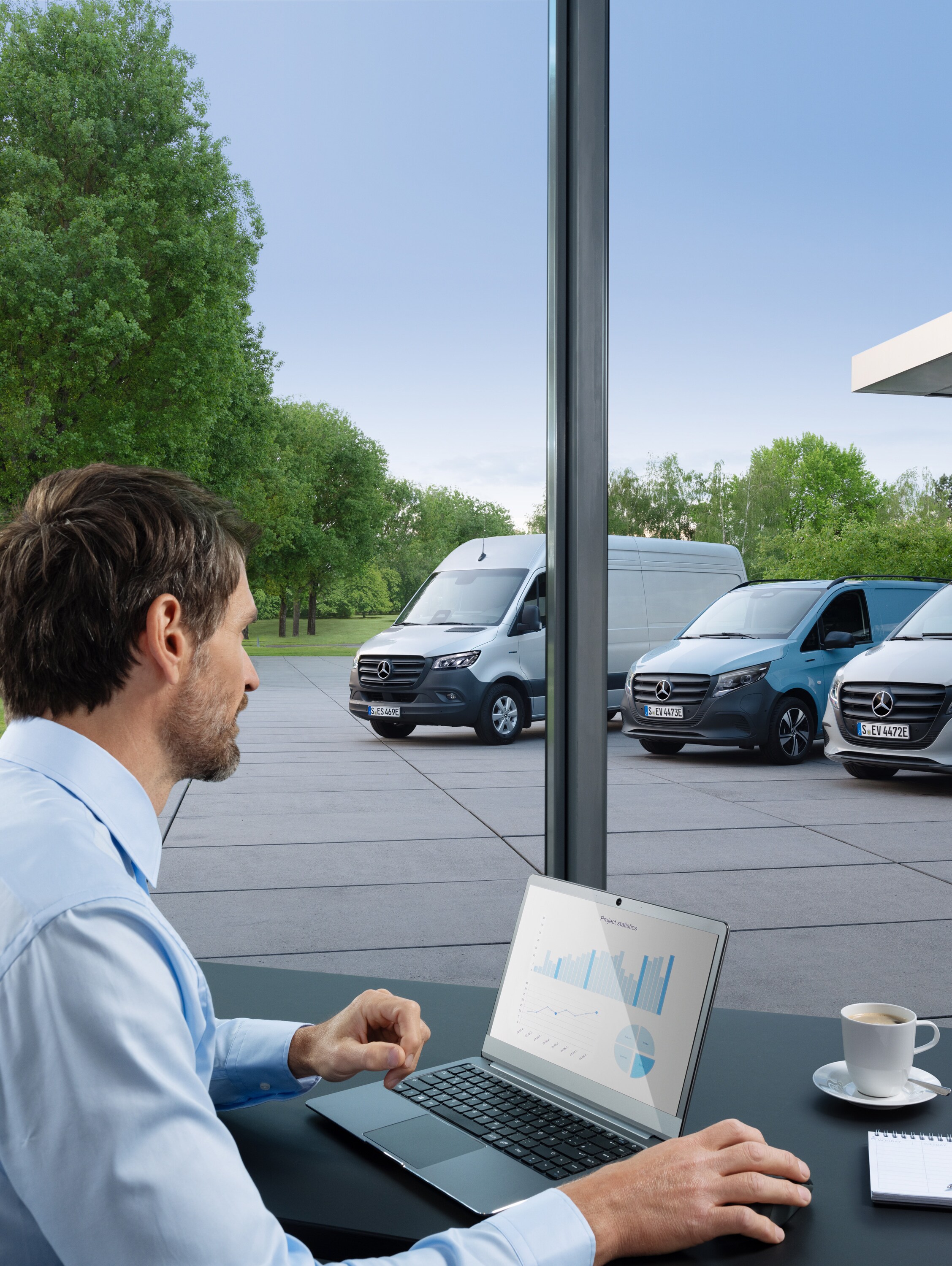 Man die met een laptop meerdere geparkeerde Mercedes-Benz bestelwagens bewaakt, symbool voor digitaal wagenparkbeheer.
