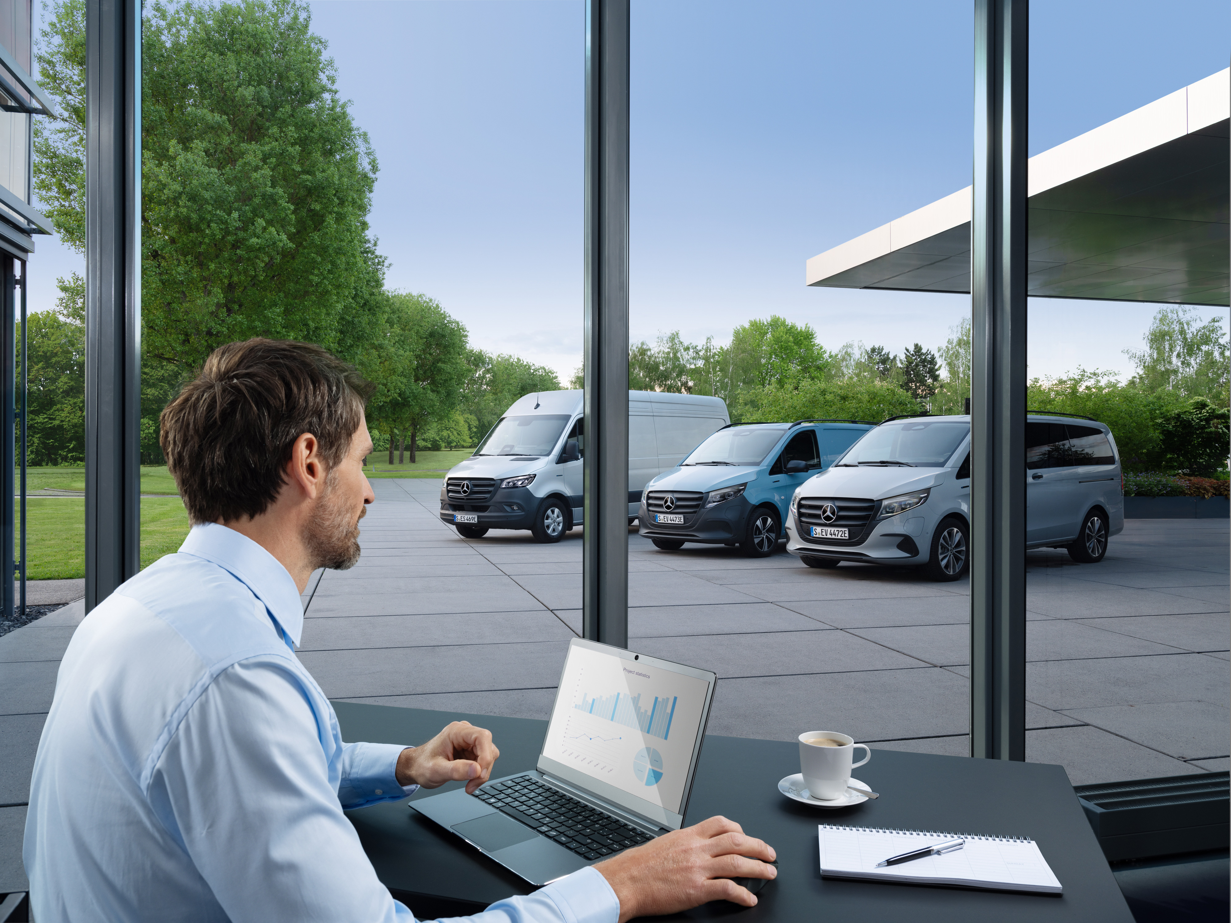 Mercedes-Benz | Bedrijfswagentechnologie | Van Uptime Monitor Man die met een laptop meerdere geparkeerde Mercedes-Benz bestelwagens bewaakt, symbool voor digitaal wagenparkbeheer.
