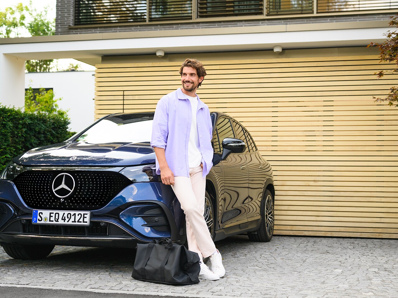 Man tegen blauwe Mercedes-Benz EQE SUV. 