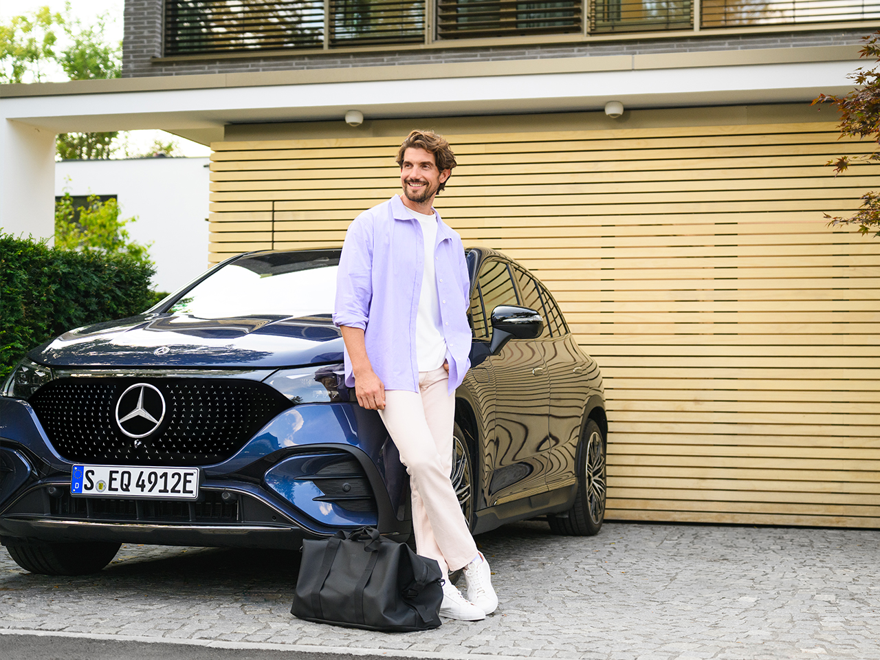 Impact voor bedrijven. Man tegen blauwe Mercedes-Benz EQE SUV.