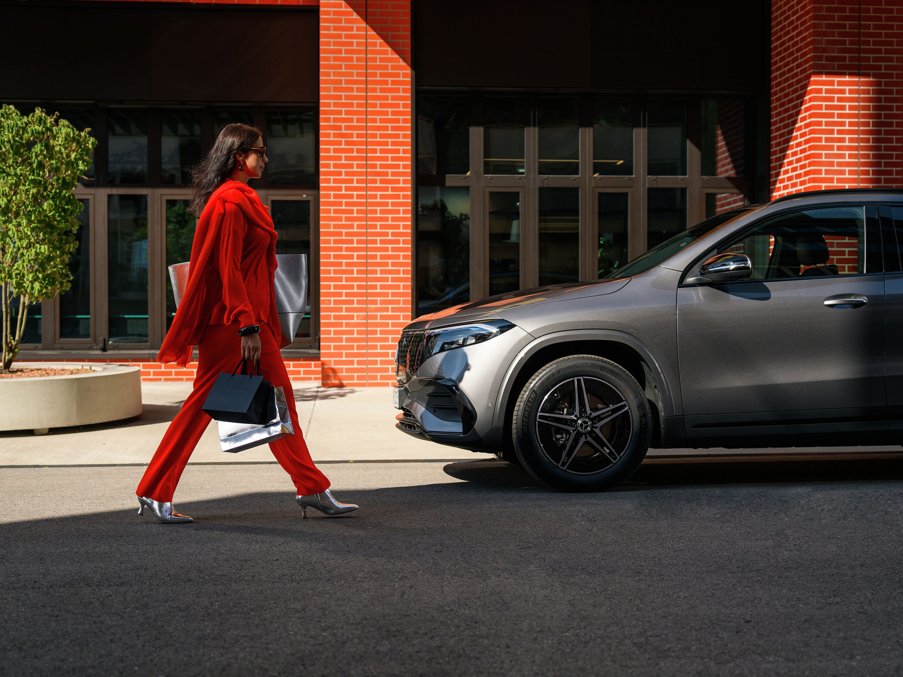 Zakenvrouw loopt naar grijze EQA van Mercedes-Benz. 