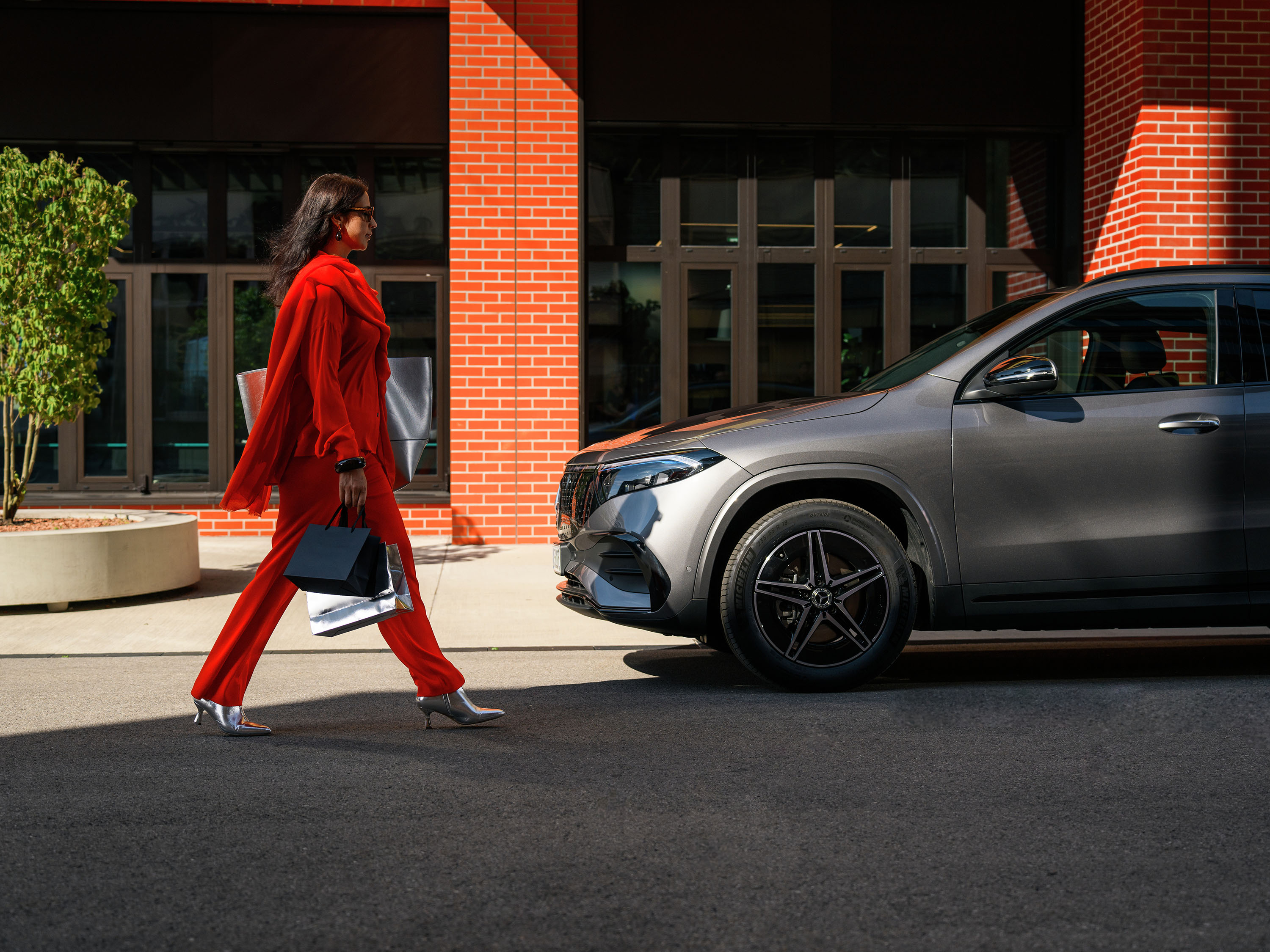 Wat kan u doen? Zakenvrouw loopt naar grijze EQA van Mercedes-Benz.
