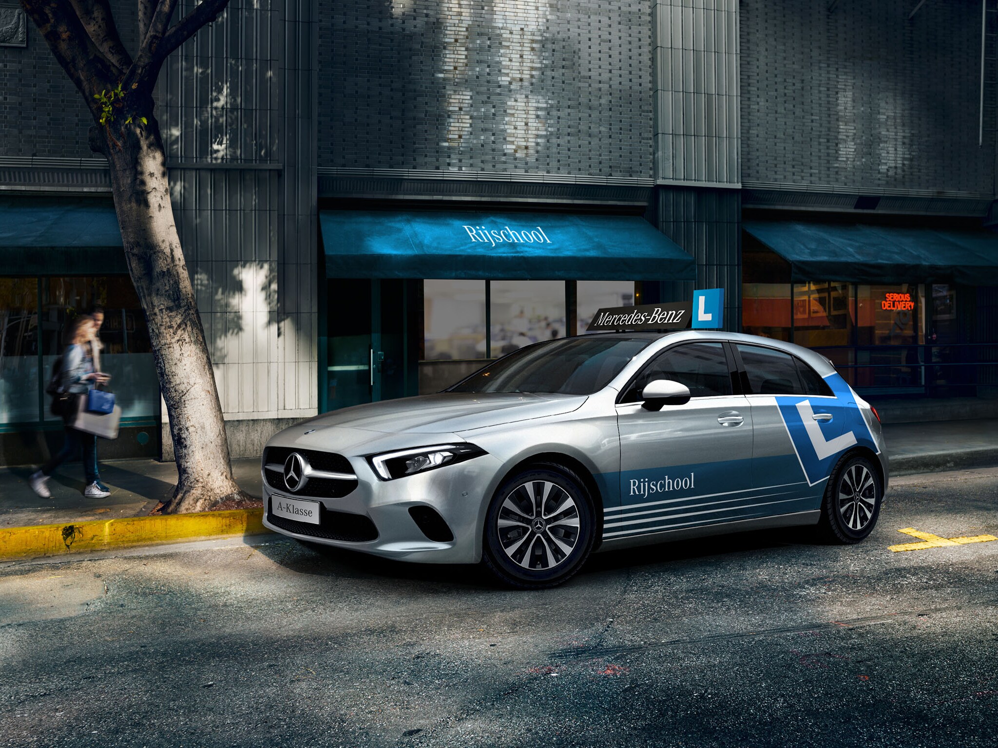 Het beeld toont de zijkant van een grijze Mercedes-Benz A-Klasse lesauto.