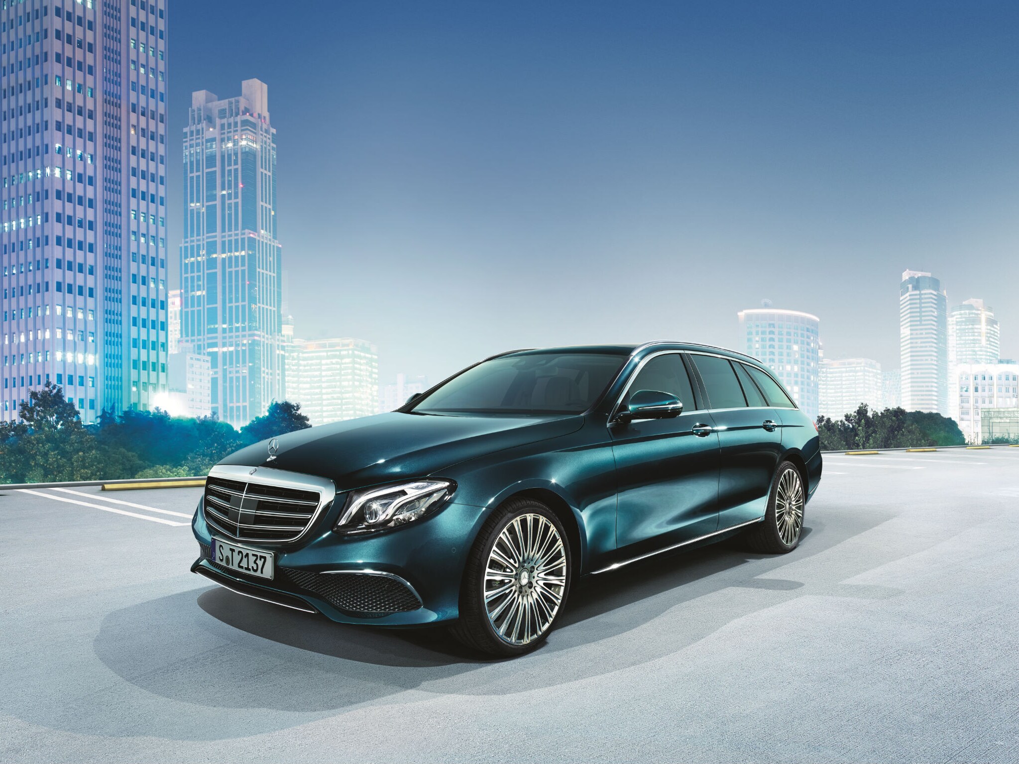 Het beeld toont een Mercedes-Benz E-Klasse op een parking met op de achtergrond gebouwen.