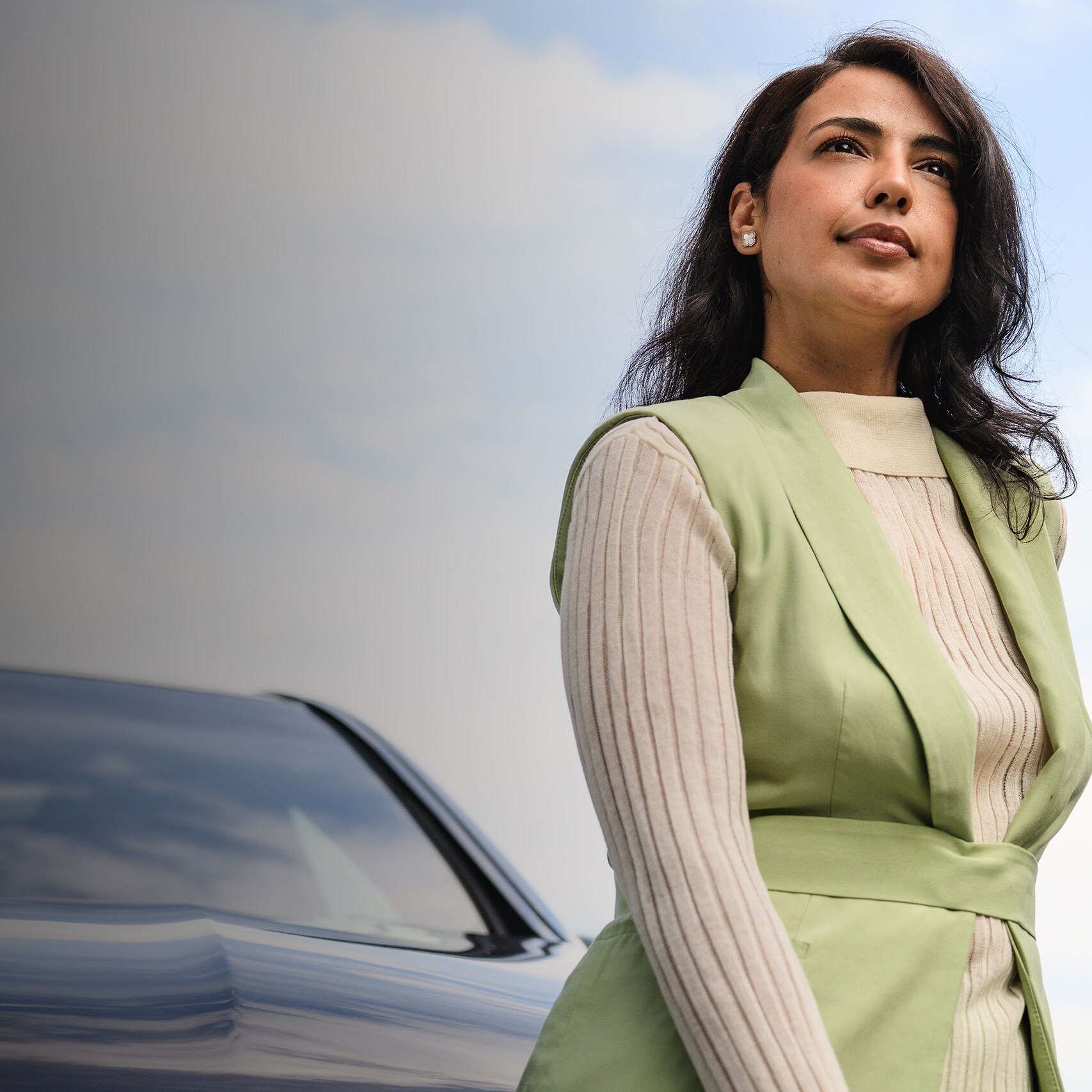 Een persoon die&nbsp;voor een voertuig Mercedes-Benz staat en in de verte kijkt.
