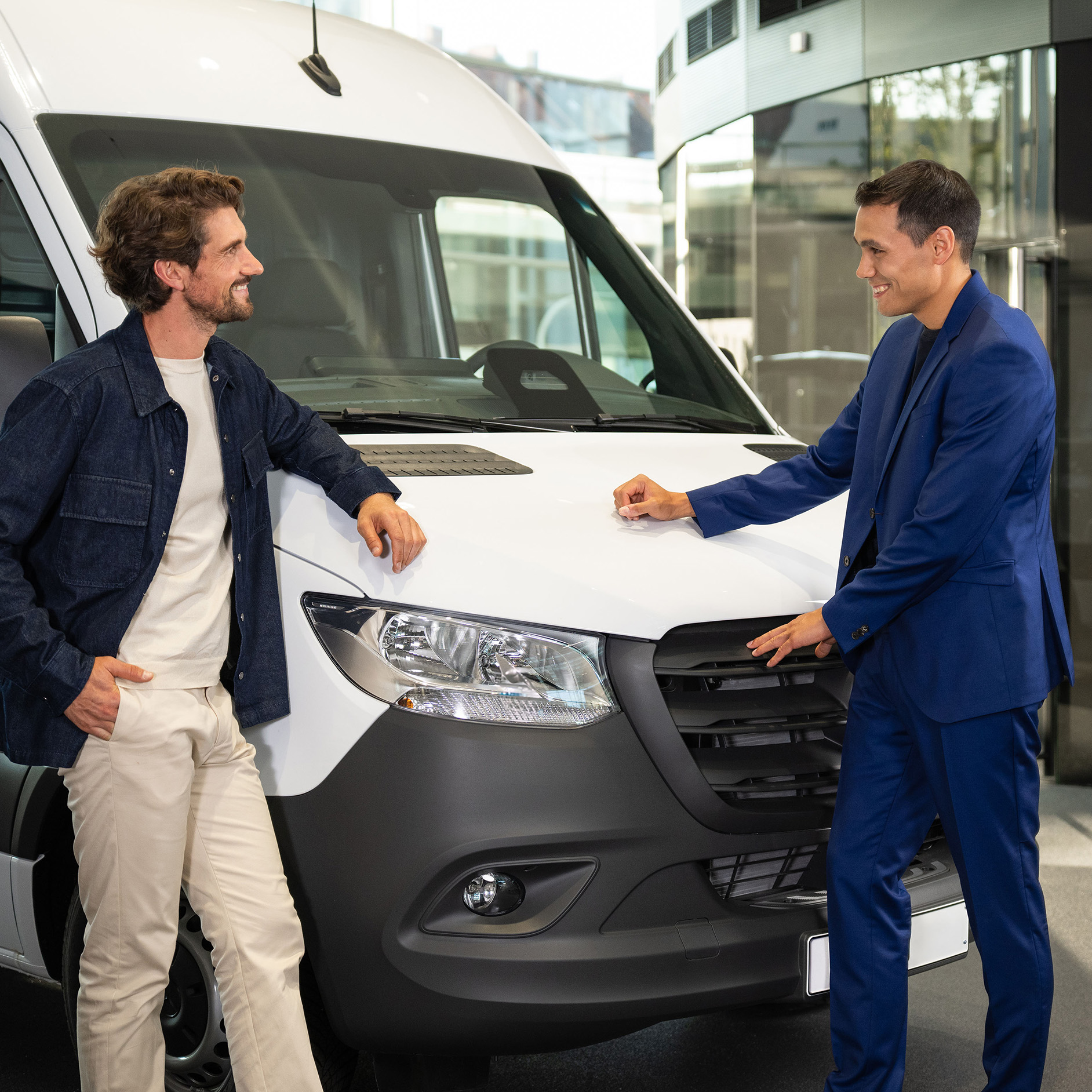 Financieringsaanbieding voor uw nieuwe Mercedes-Benz bedrijfswagen Twee personen leunen tegen een Mercedes-Benz bestelwagen en zijn in gesprek.