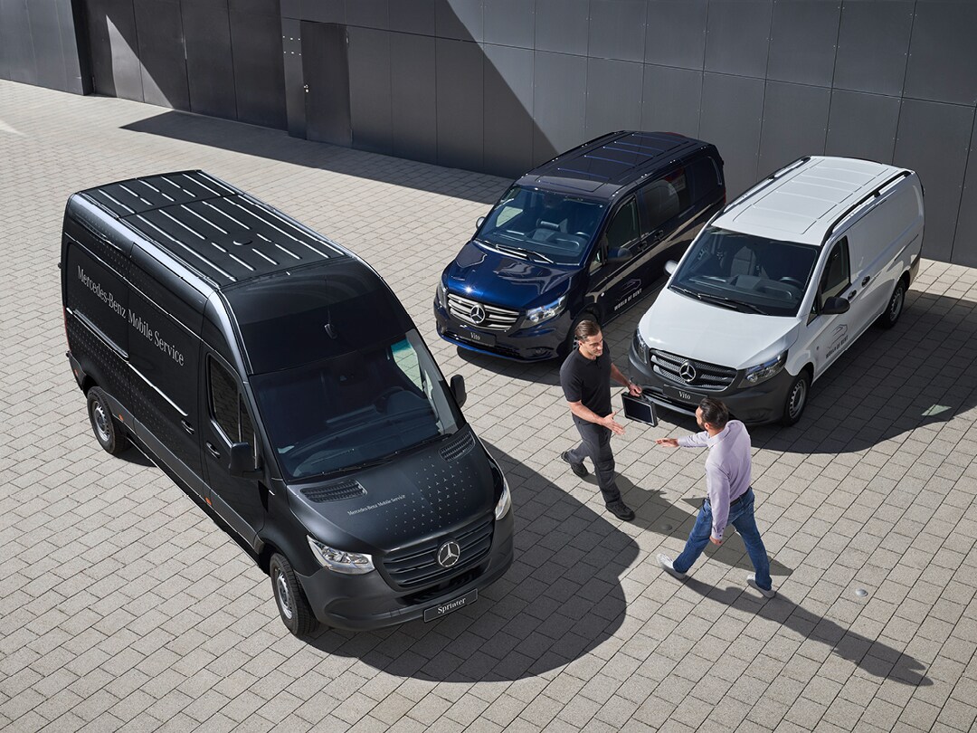 Twee mannen praten in een Mercedes-Benz showroom voor een rode EQV