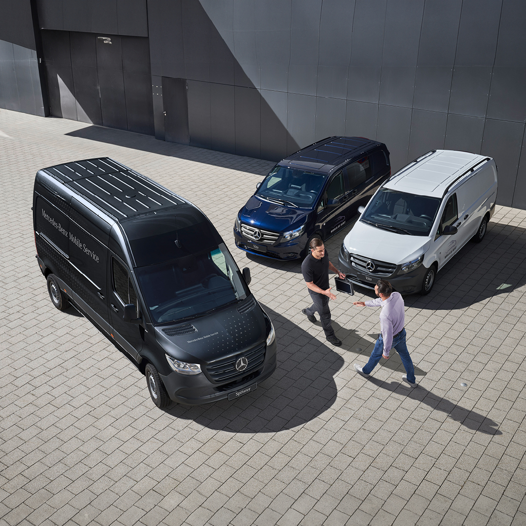 Twee mannen in gesprek in een Mercedes-Benz showroom met een rode EQV op de achtergrond. Twee mannen praten in een Mercedes-Benz showroom voor een rode EQV