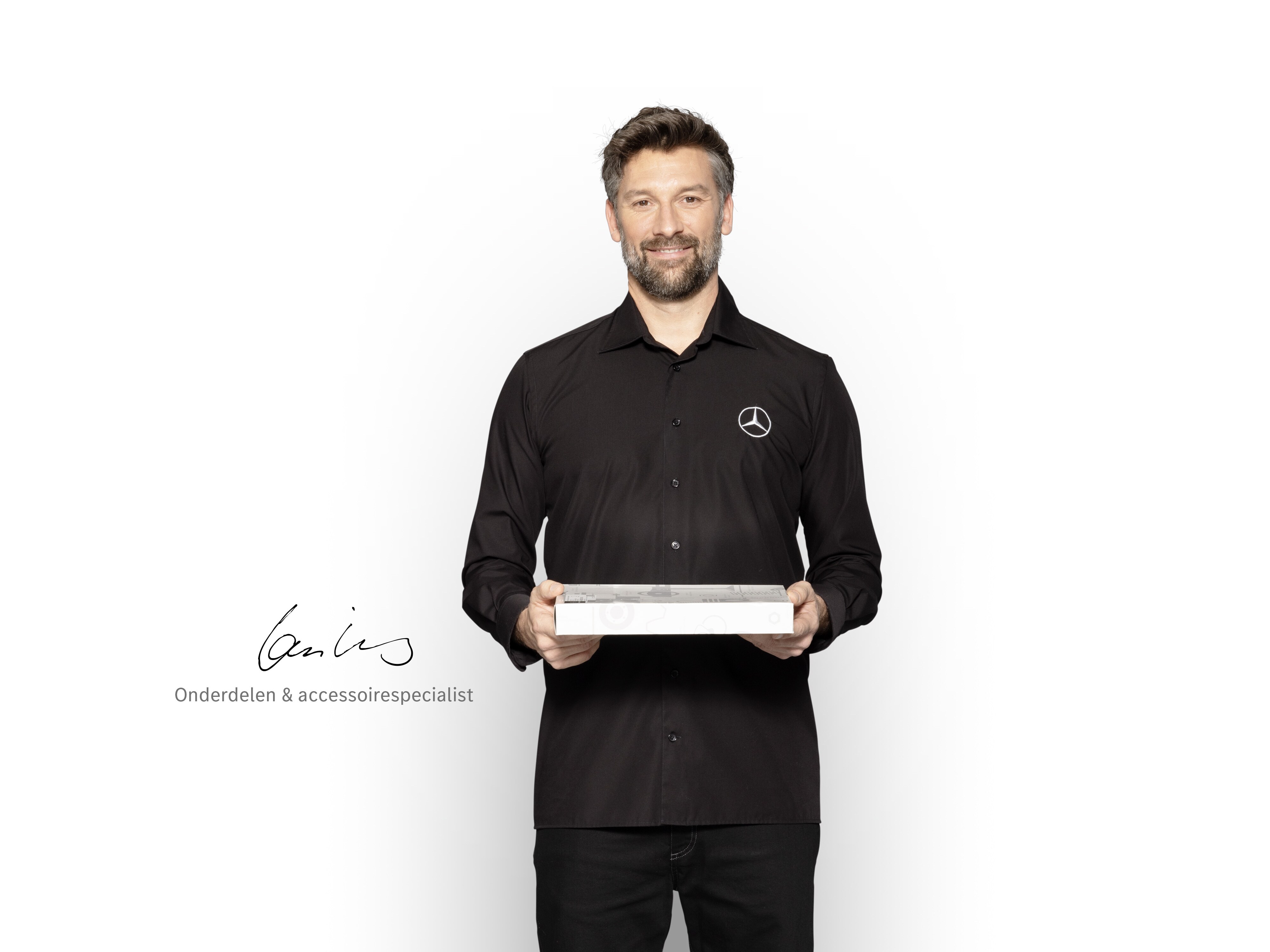 Mercedes-Benz Monteur met een doos in zijn handen om Mercedes-Benz Originele Onderdelen te tonen.